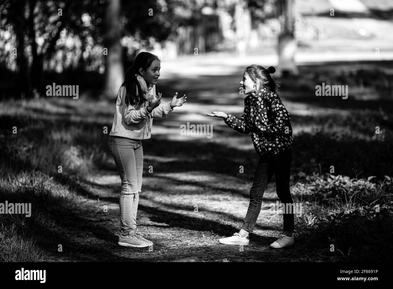 Two girlfriends are talking emotionally outdoors. Black and white photo. Stock Photo