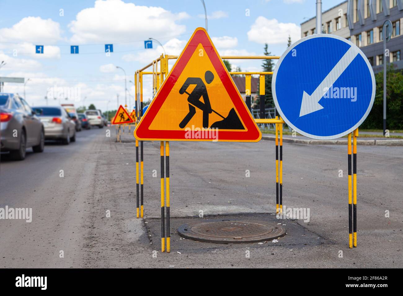 Asphalt road repairs, yellow warning triangle signs about road works ...