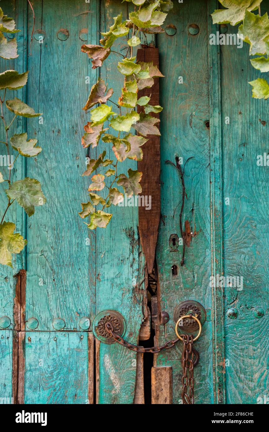 Old green wooden door with metal chain and door handles close-up Stock Photo
