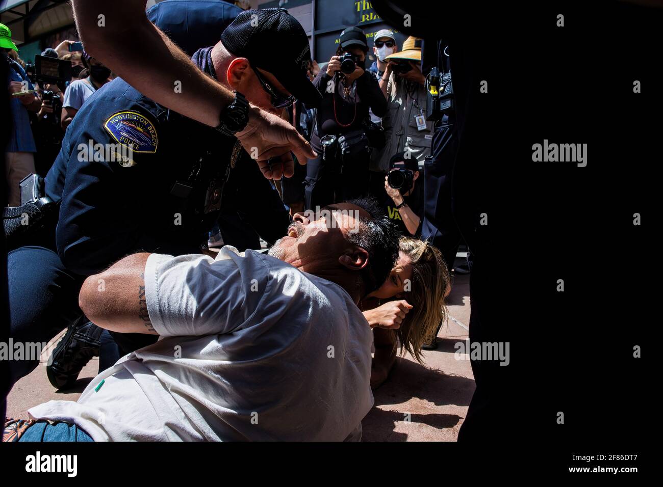 A White Lives Matter protester is shoved to the ground by counter-protesters and eventually surround by police during the demonstration. Upon word spreading amongst various social media and messaging platforms that there was to be a 'White Lives Matter' protest at the Huntington Beach Pier at 1pm, a large group of counter protesters arrived at the pier to stop the 'White Lives Matter' protest. The day resulted to clashes between counter protesters and white lives matter protesters both verbal and physical. Stock Photo