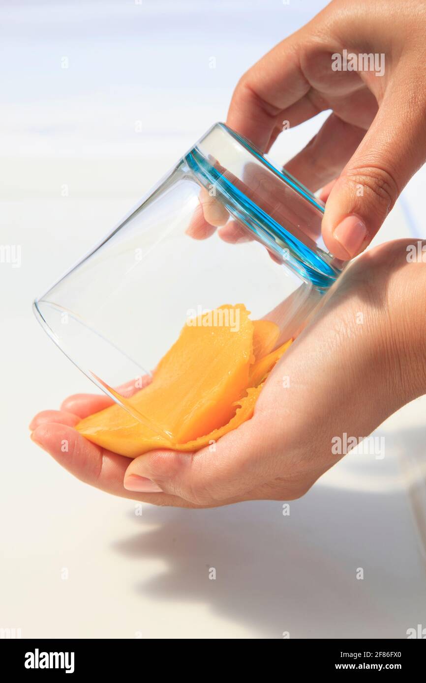 Mango being cut and prepared with 2 hands Stock Photo - Alamy