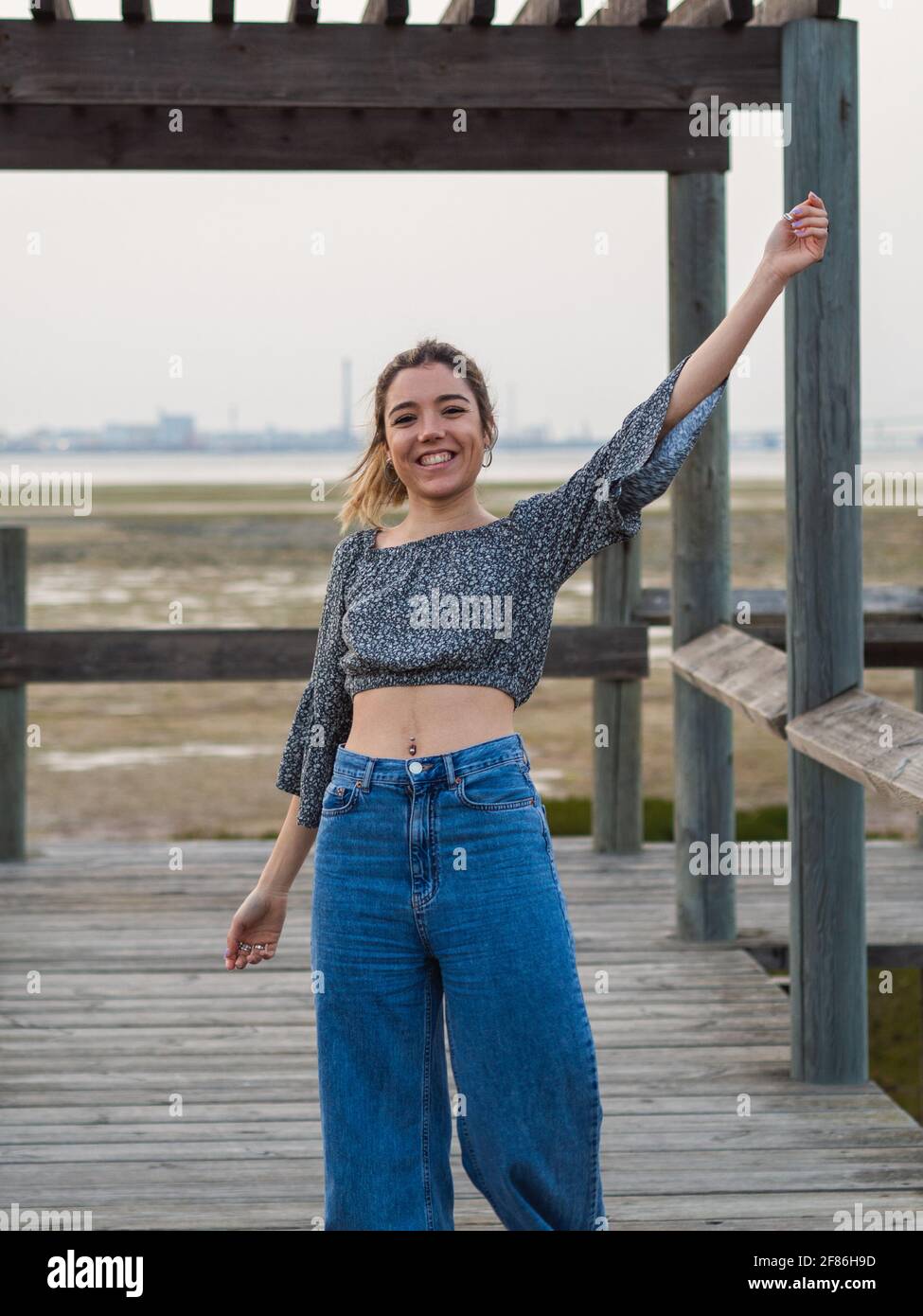 Cheerful young Spanish girl wearing jeans and a gray blouse is spending  leisure time on the dock Stock Photo - Alamy