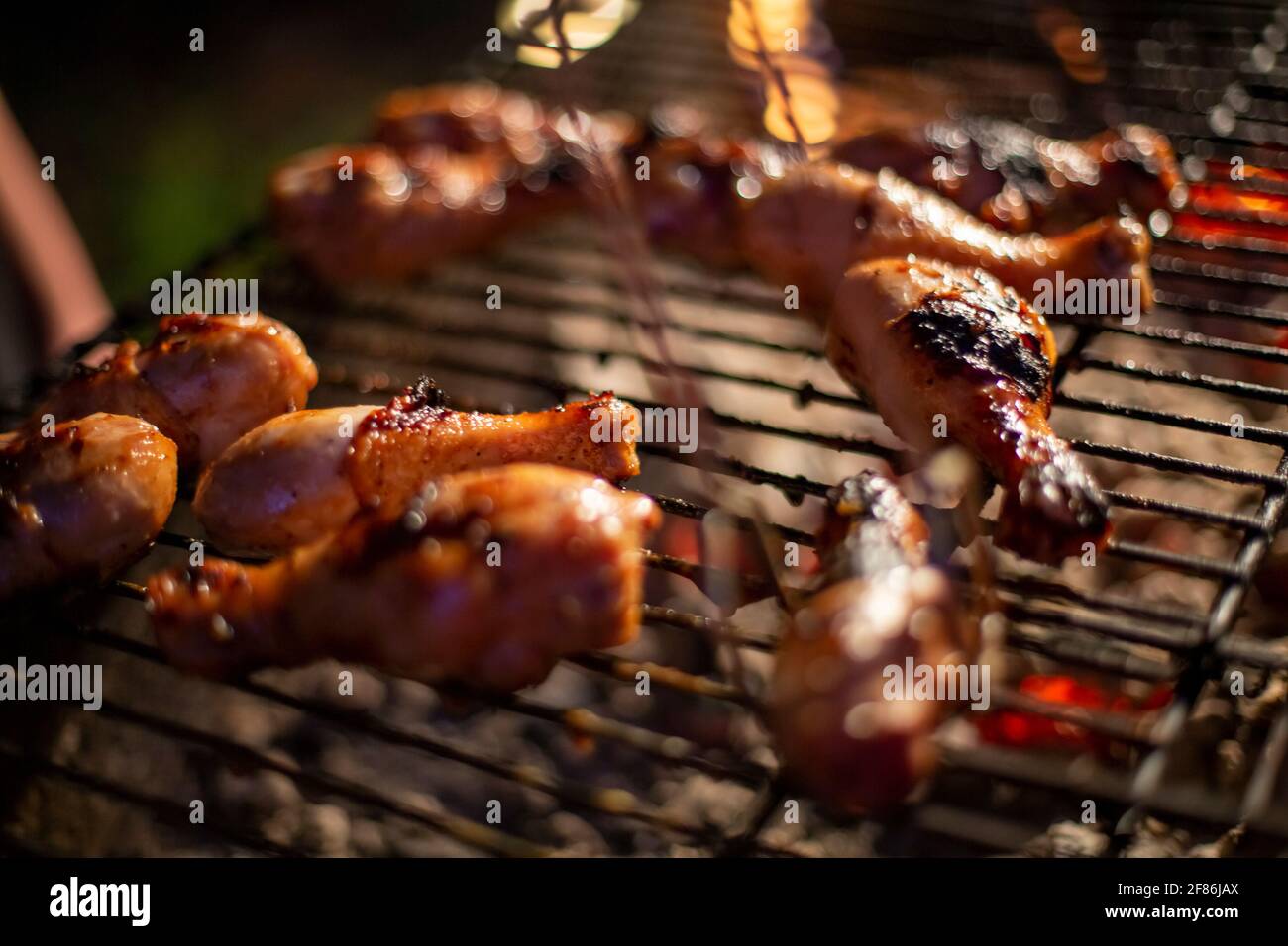 chicken drumsticks are grilled on a barbecue grill in the evening Stock