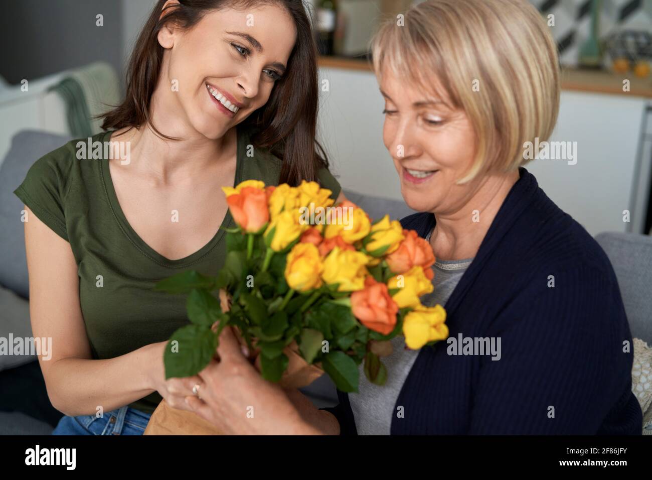 Daughter giving a loving mother a bouquet of flowers Stock Photo