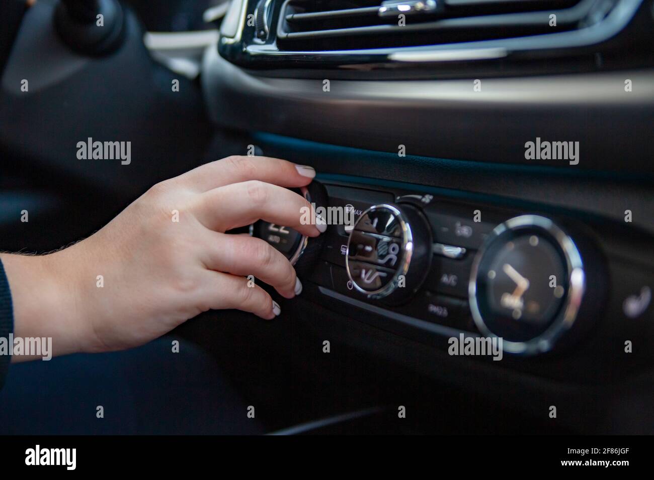 Woman's hand switches the air conditioning in the car. Driver turning