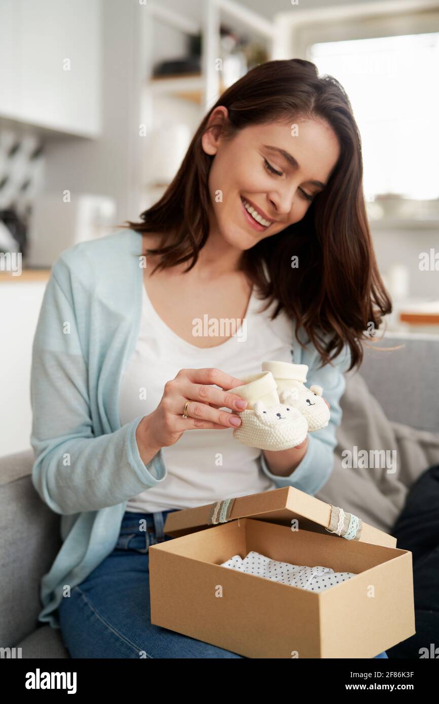 Happy woman puts knit baby booties into gift box Stock Photo - Alamy