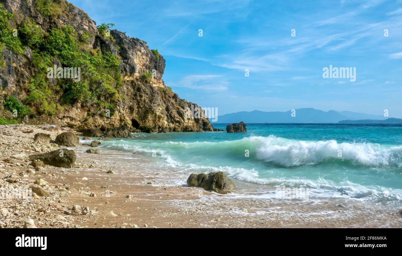 Motion blurred waves breaking on a secluded rocky beach in the tropical resort area of Puerto Galera on Mindoro Island in the Philippines. Stock Photo