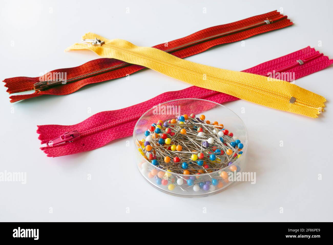 pink, red, yellow zippers and box of round pin . Selective Focus. isolated White Background Stock Photo
