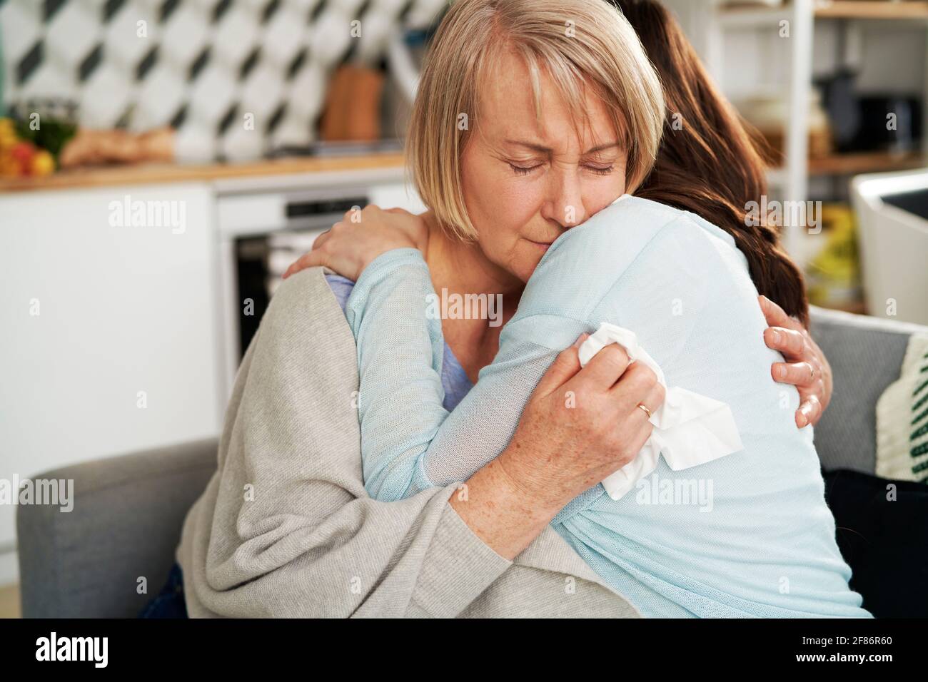 Woman hugging sad senior woman Stock Photo