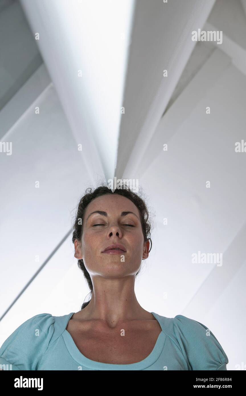 Serene businesswoman standing below angled ceiling Stock Photo
