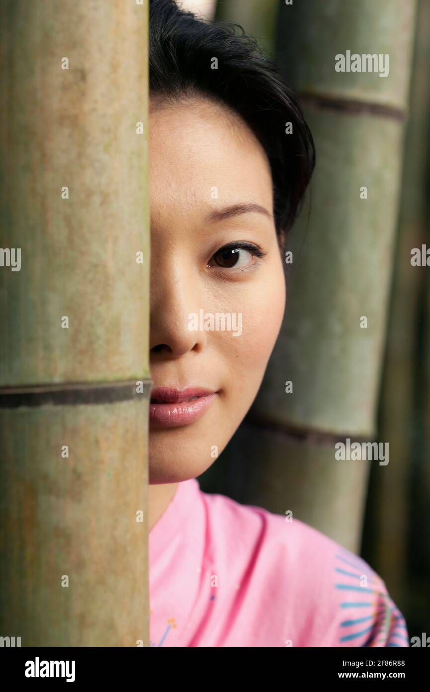 Close up portrait beautiful young Asian woman behind bamboo Stock Photo