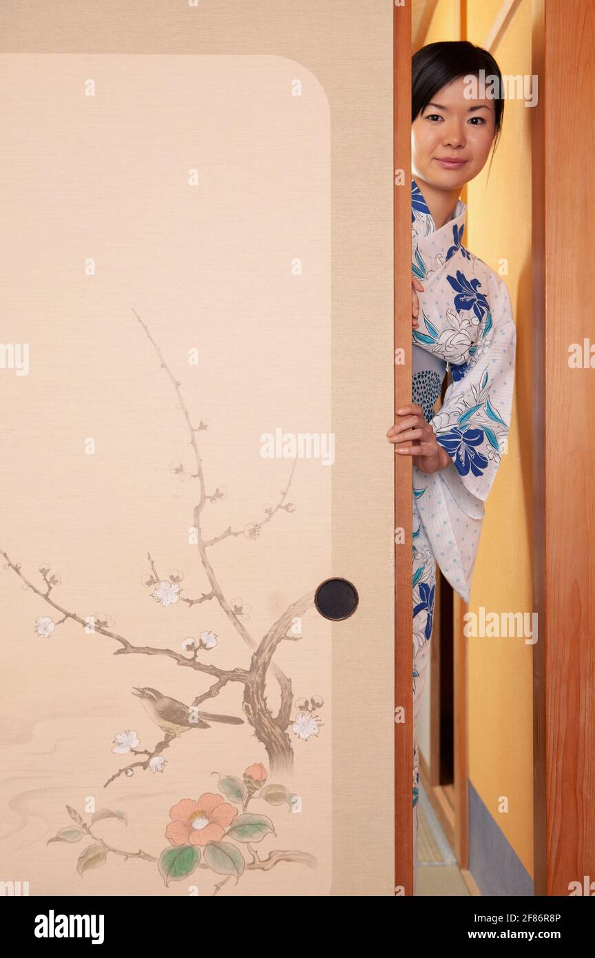 Portrait beautiful young woman in kimono behind painted door Stock Photo