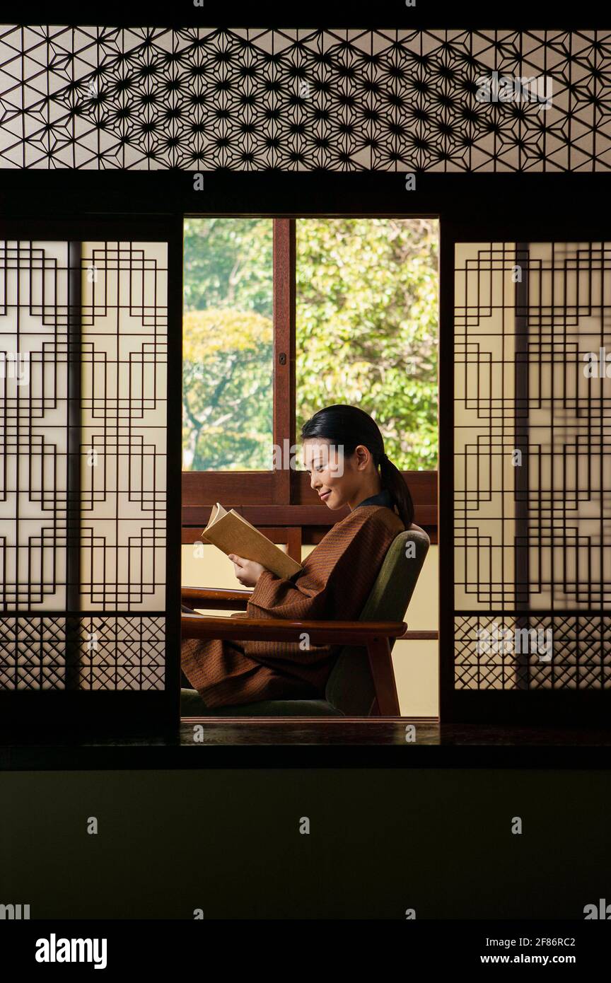 Young woman reading book in ornate shoji doorway Stock Photo
