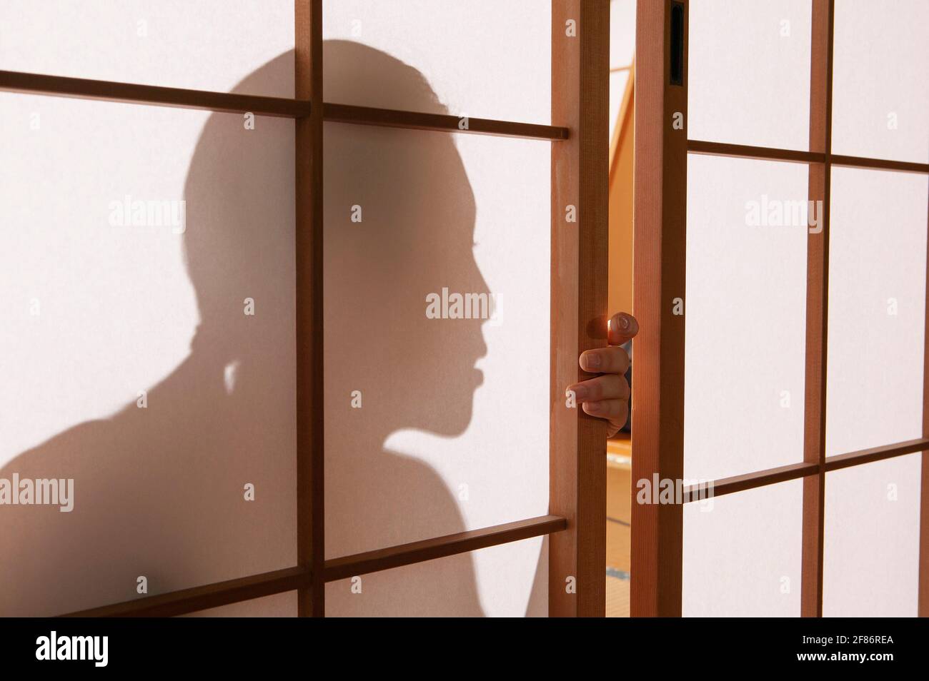 Close up shadow young woman lurking behind shoji doors Stock Photo