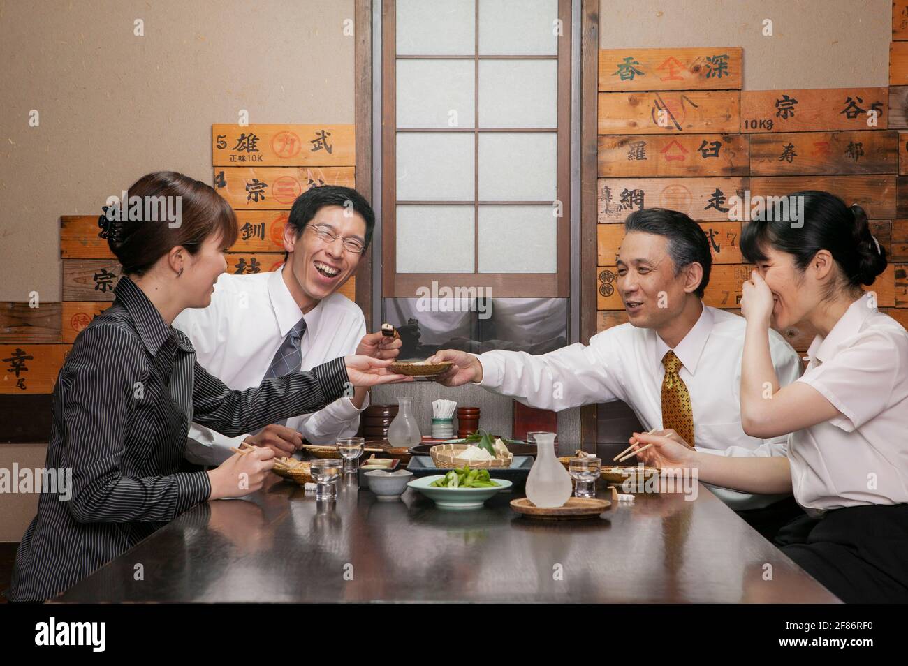 Happy Japanese business people enjoying sushi lunch in restaurant Stock Photo