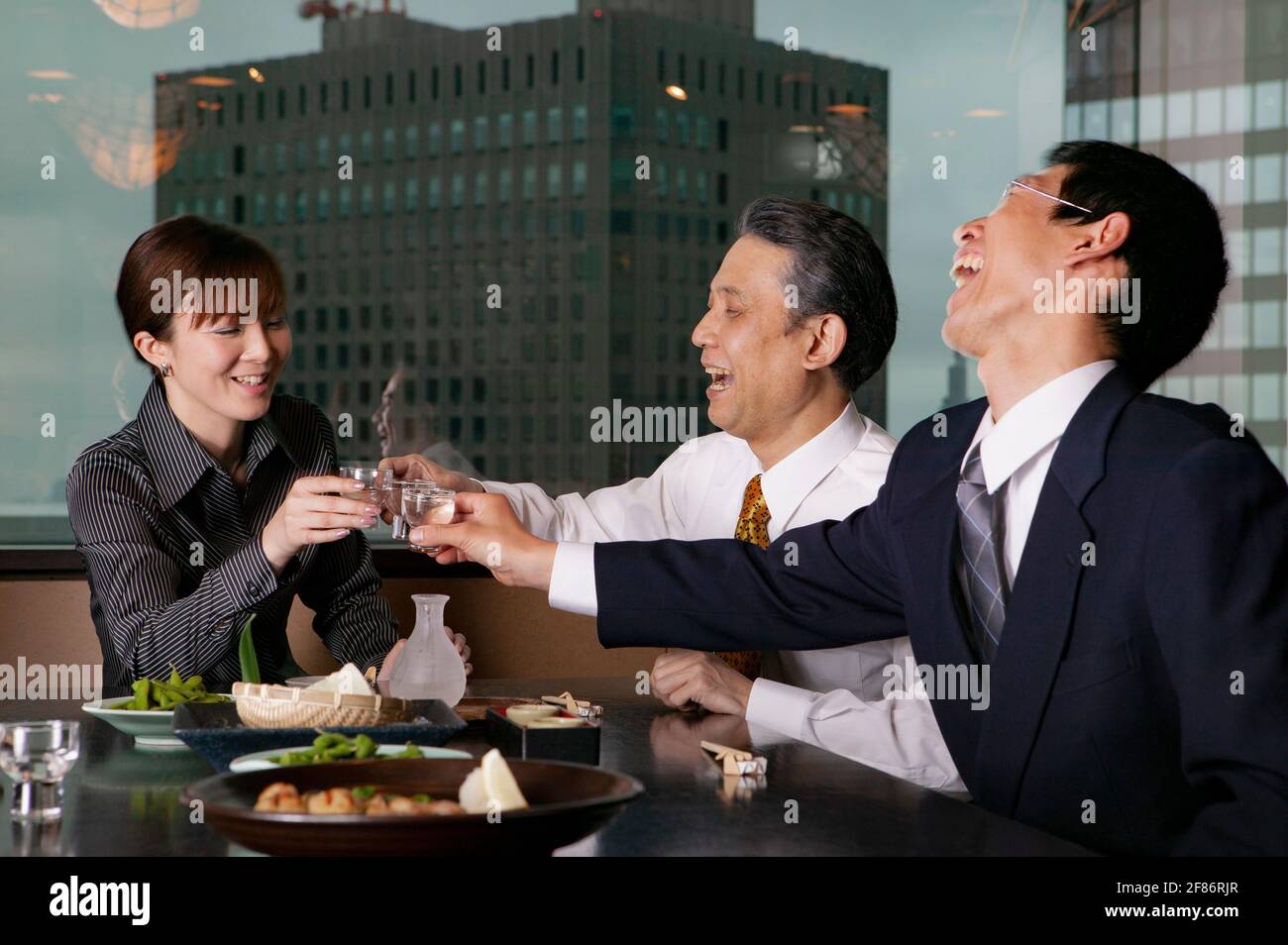 Happy business people toasting sake in highrise restaurant Stock Photo
