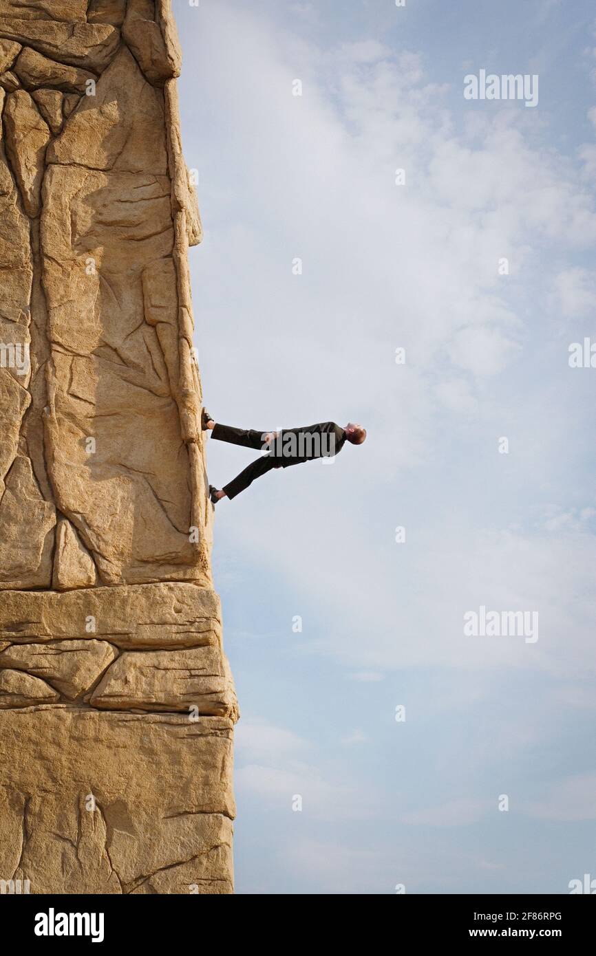 Businessman walking up steep rock face