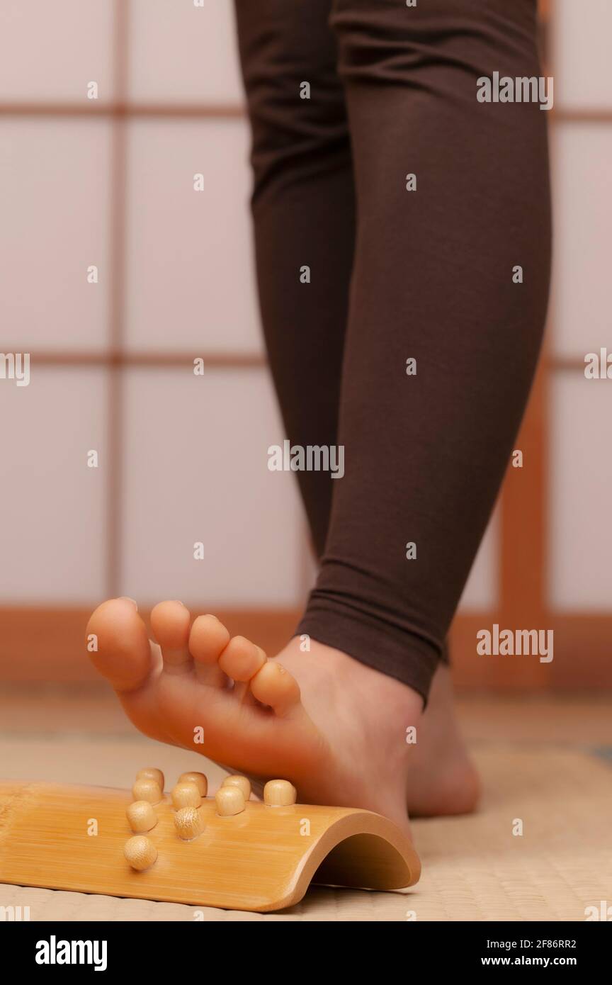 Close up young barefoot woman using foot massager in spa Stock Photo