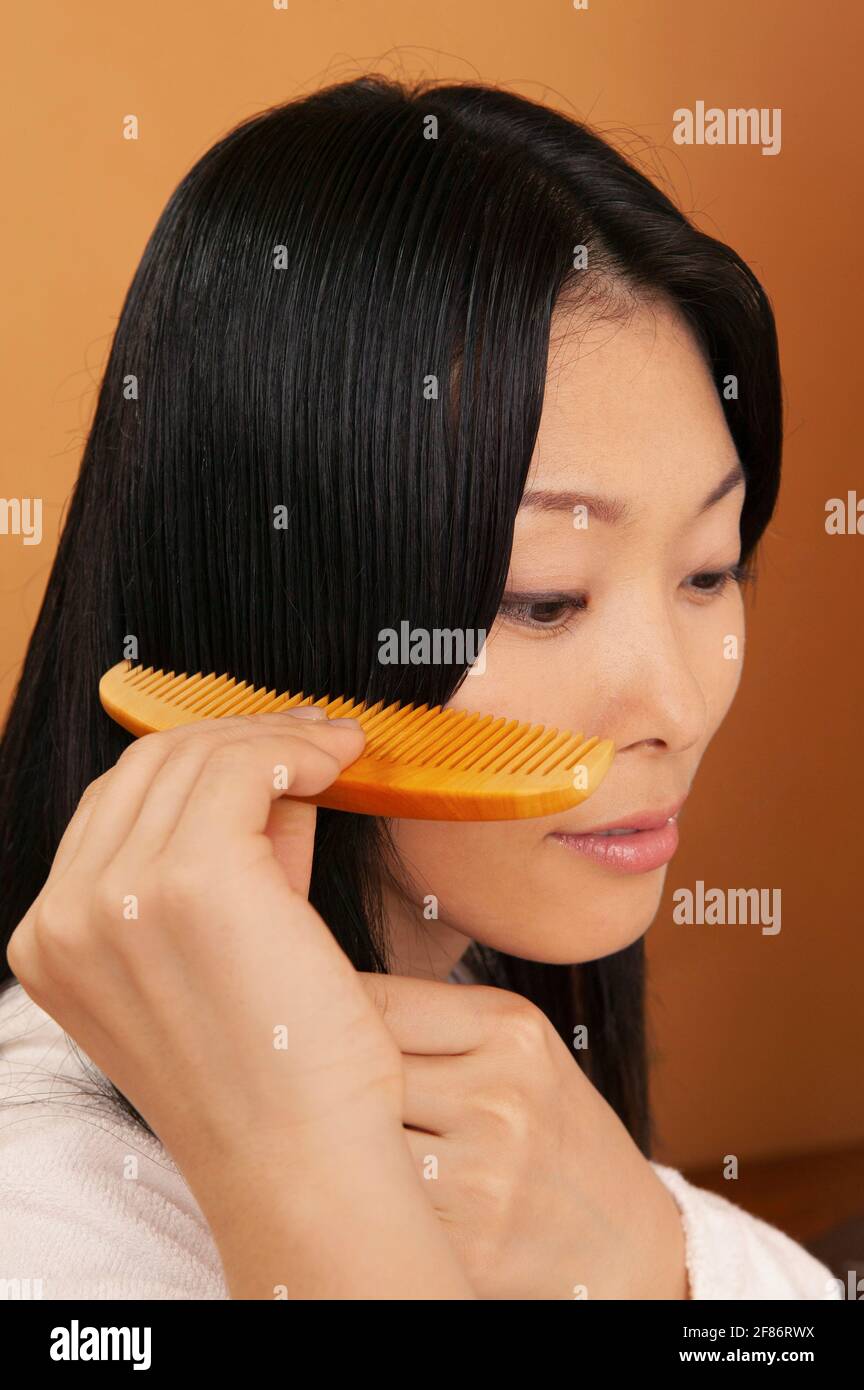 Close up beautiful young woman combing hair Stock Photo