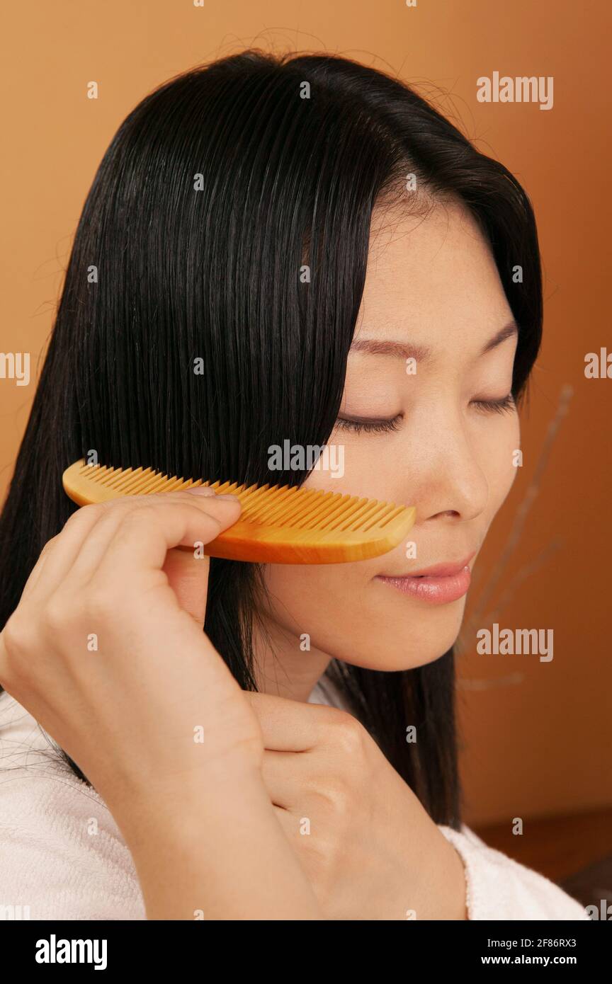 Serene beautiful young woman combing hair Stock Photo
