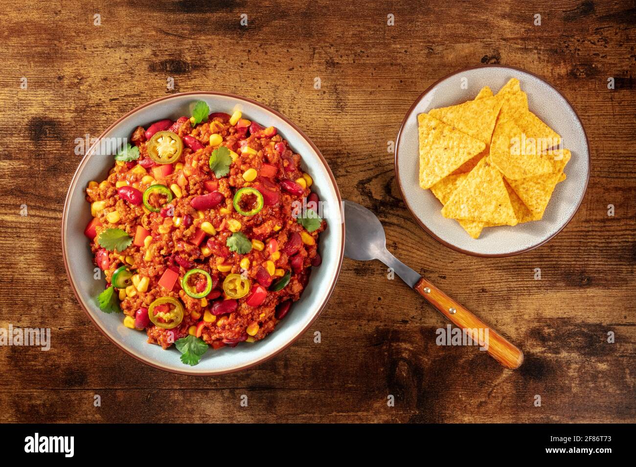 Chilli con carne with nachos on a dark rustic wooden background Stock Photo