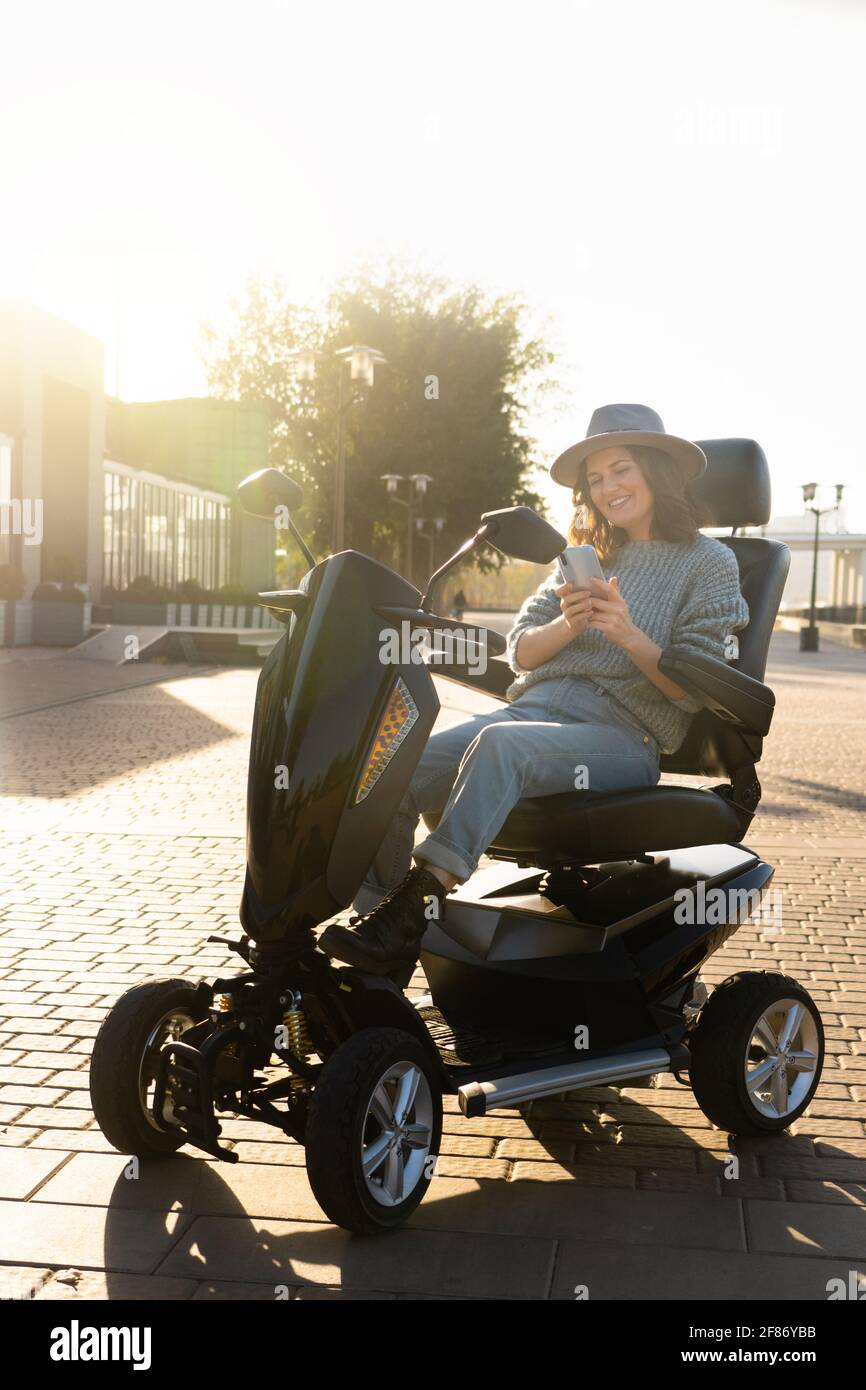 Woman tourist riding a four wheel mobility electric scooter on a city street. Stock Photo
