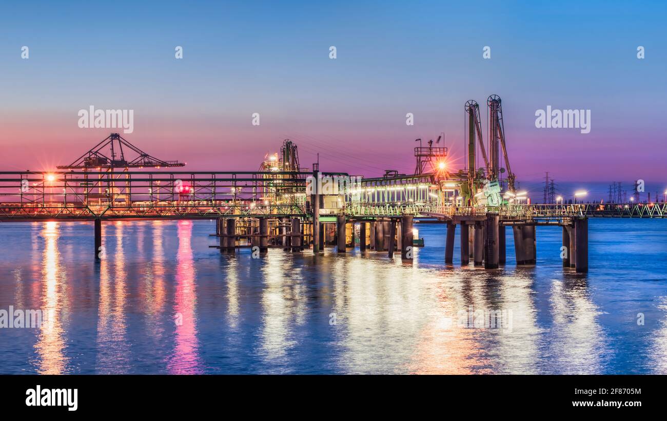 Industrial pier near petrochemical production plant during a colorful sunset, Port of Antwerp, Belgium Stock Photo