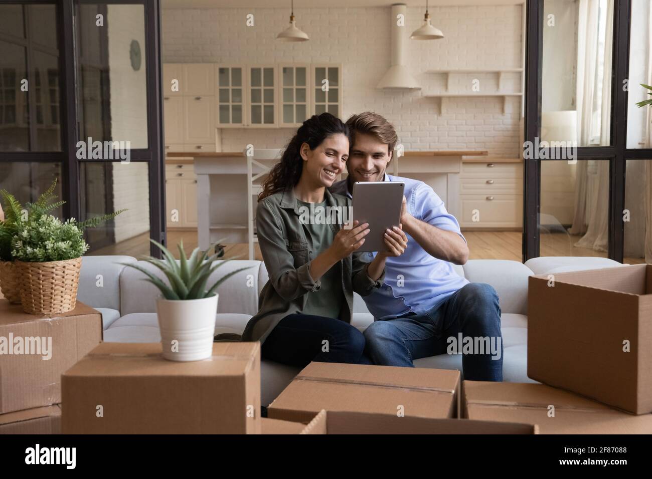 Happy couple using tablet, choosing moving service for relocation Stock Photo