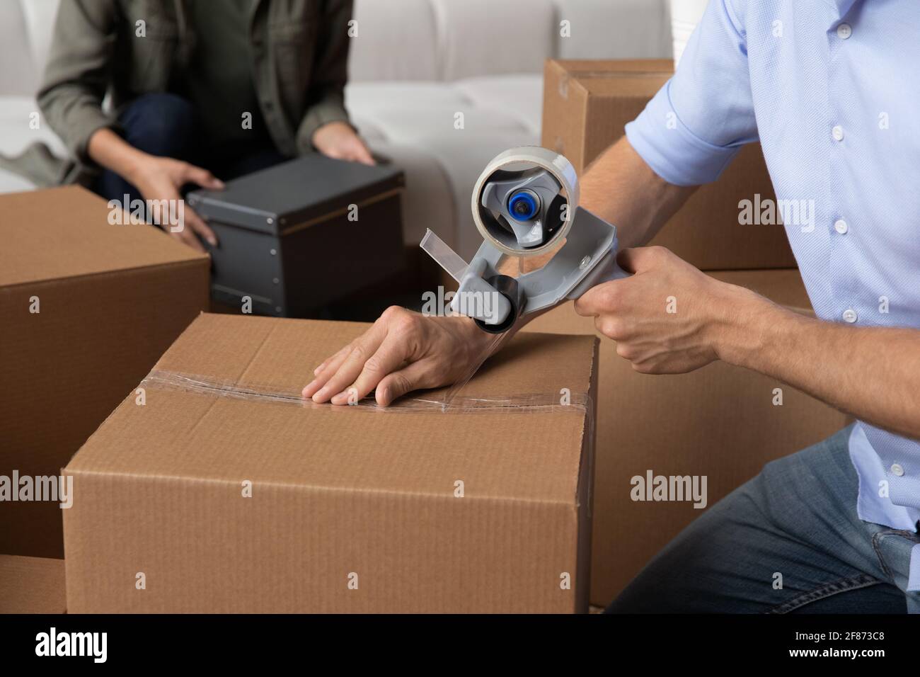 Close up family packing boxes, using adhesive tape, moving day Stock Photo