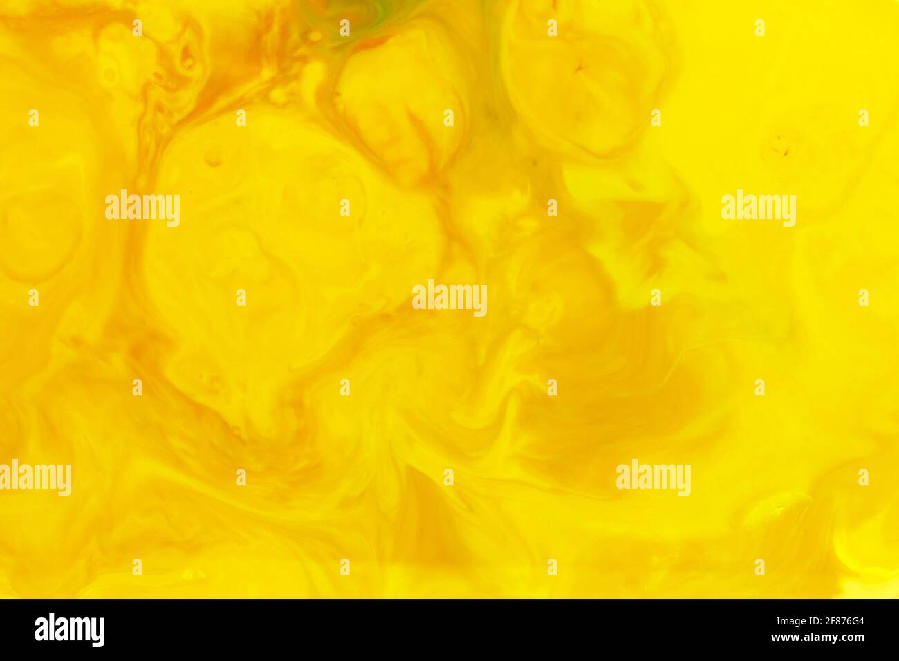 Vibrant yellow abstract amorphous background of swirling ink creating a random pattern in a full frame view for a design template Stock Photo