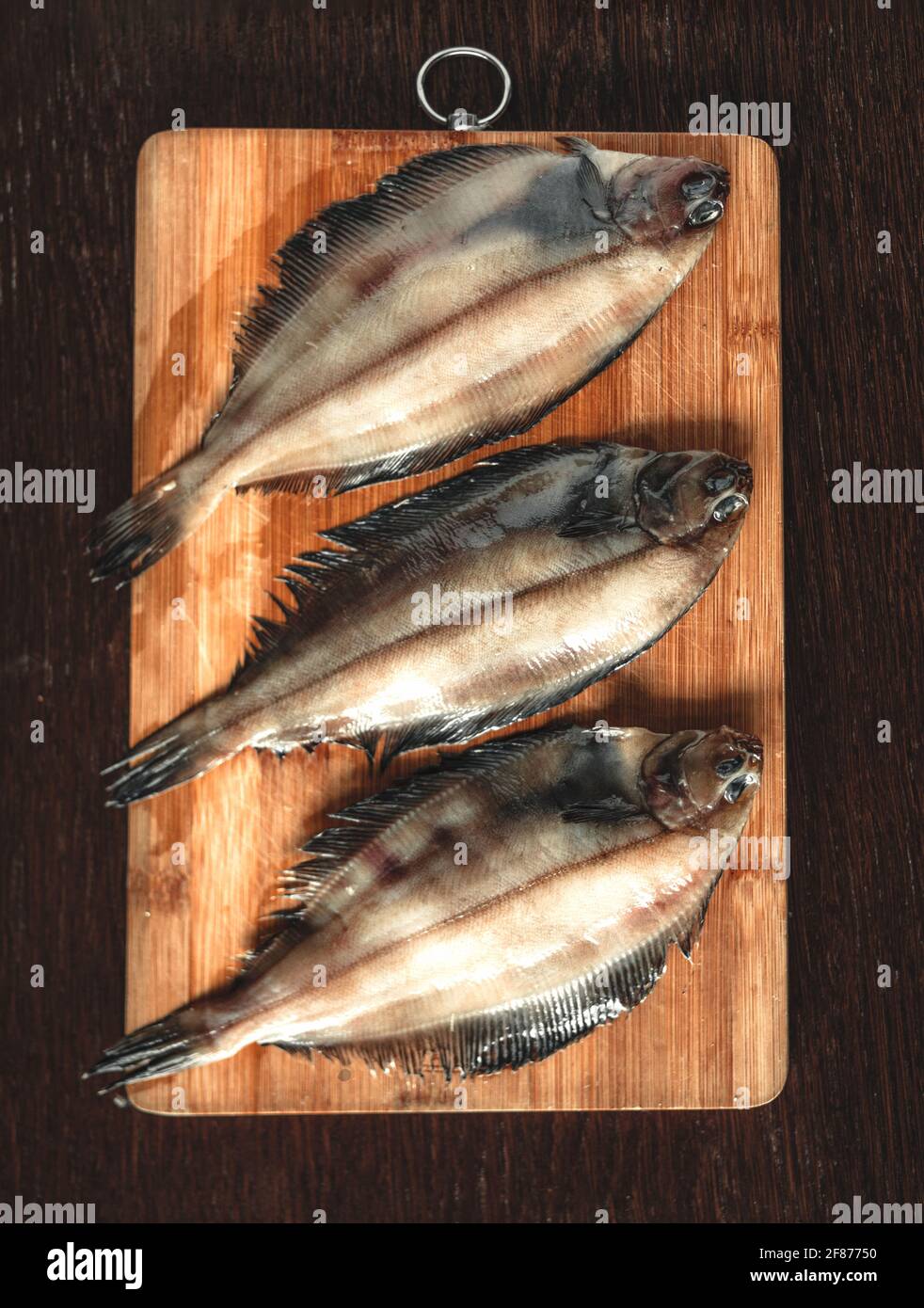 Raw flounder fish, seafood on a wooden cutting Board . Healthy eating concept. Top view Stock Photo