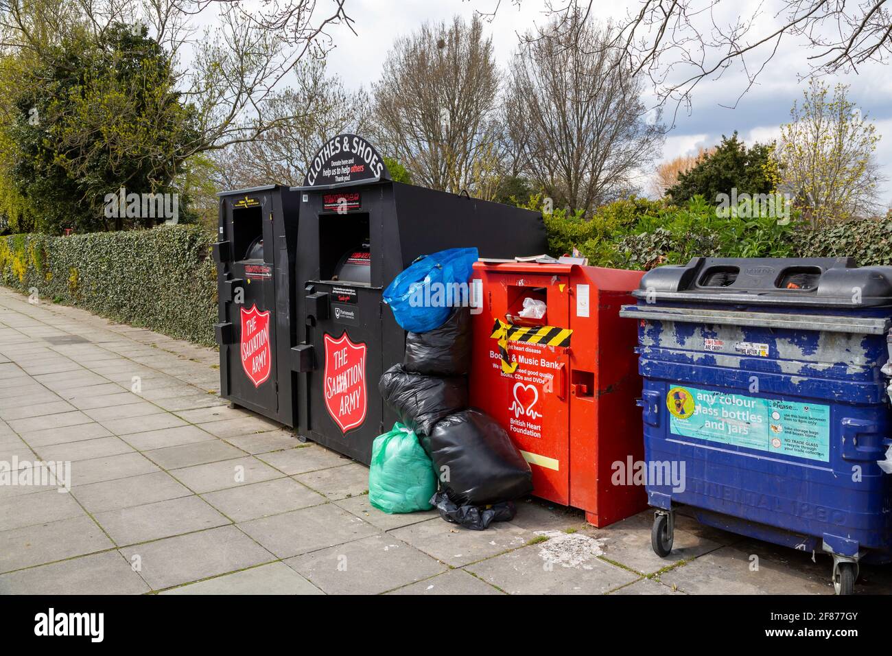 A Row of charity clothes collection bins on a street overflowing with donations Stock Photo Alamy