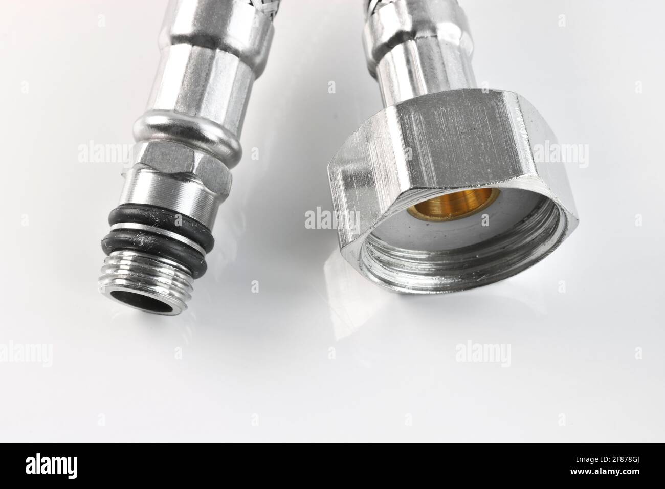 Flexible water line with connections on a light background. Plumbing