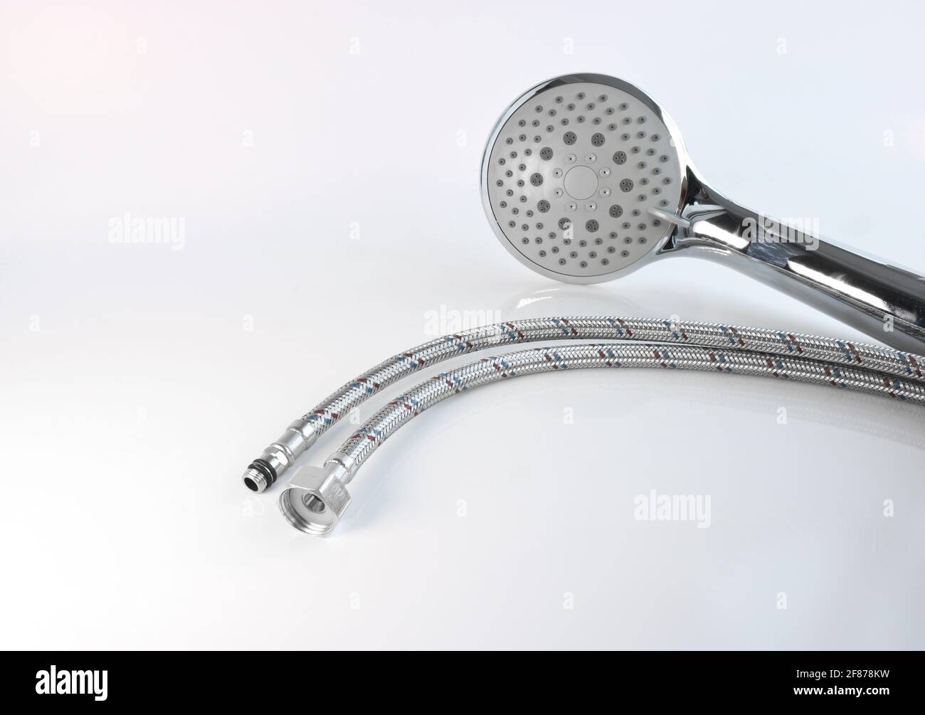 Shower head and flexible water connections on a light background. Plumbing accessories Stock