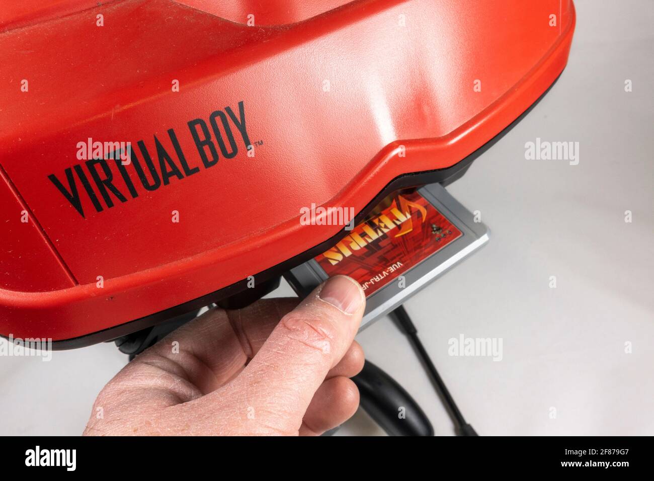 Putting a game cartridge in the slot of a Nintendo Virtual Boy table-top video game console, launched in Japan 1995, (it did not launch in Europe). Stock Photo