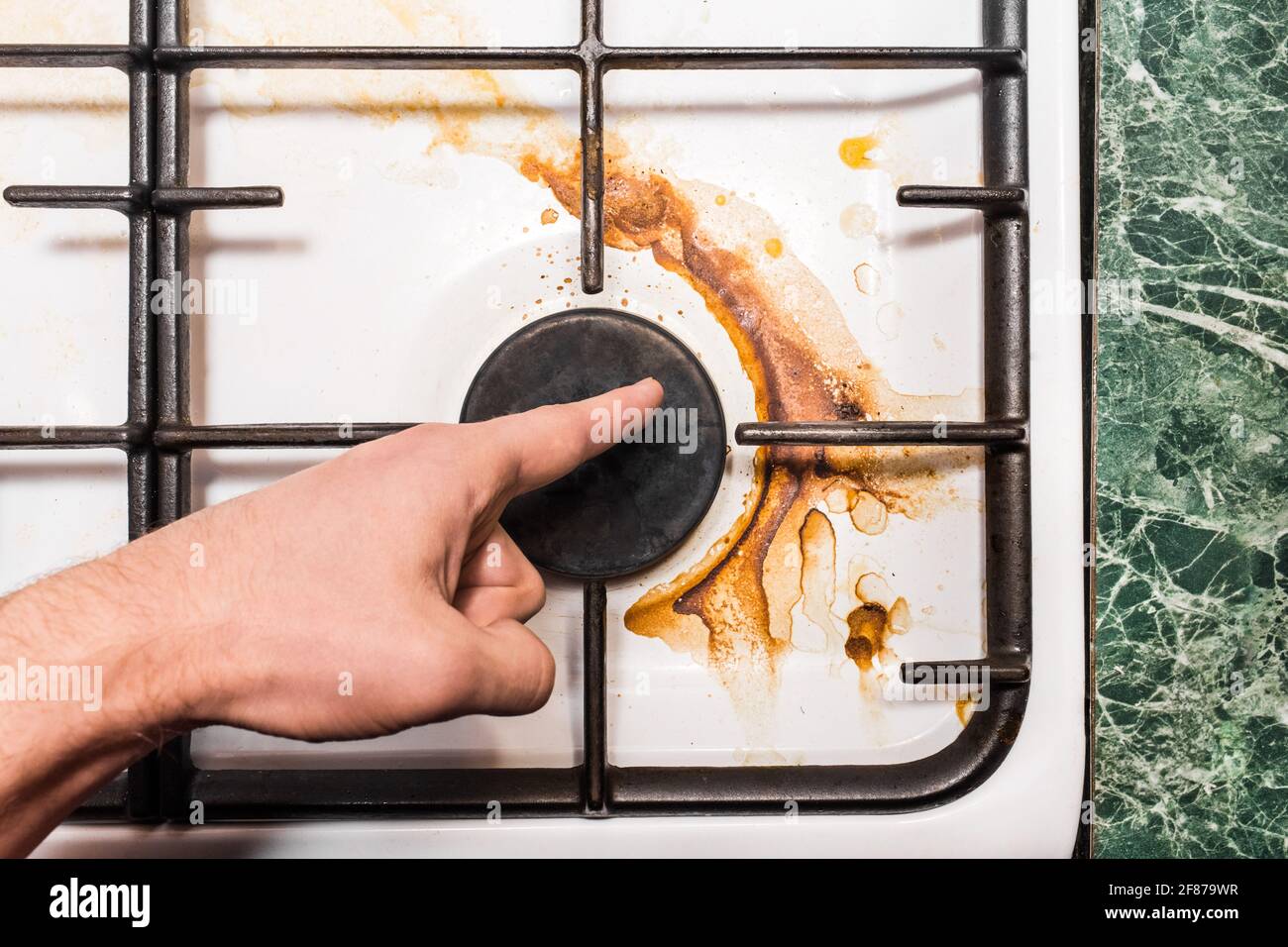 The guy's hand points a finger at the dirty plaque on the gas stove