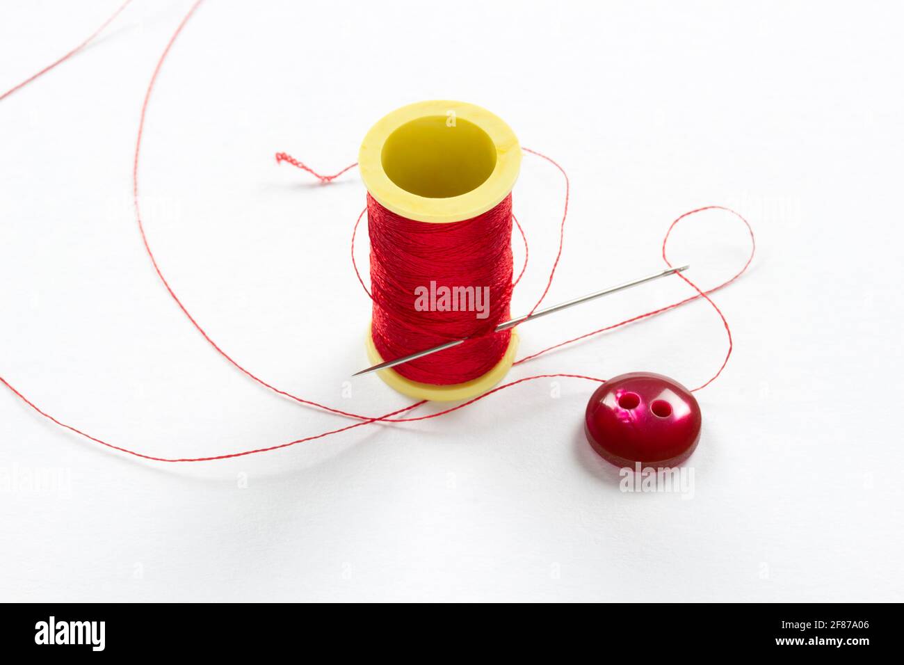 Button with two holes. Thin red thread Stock Photo - Alamy