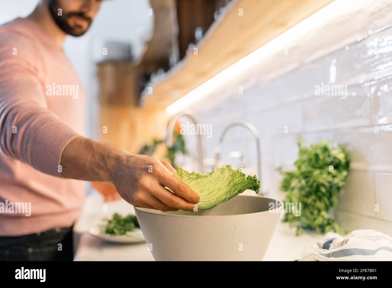 Unrecognized handsome man preparing salad in the kitchen. Stock Photo