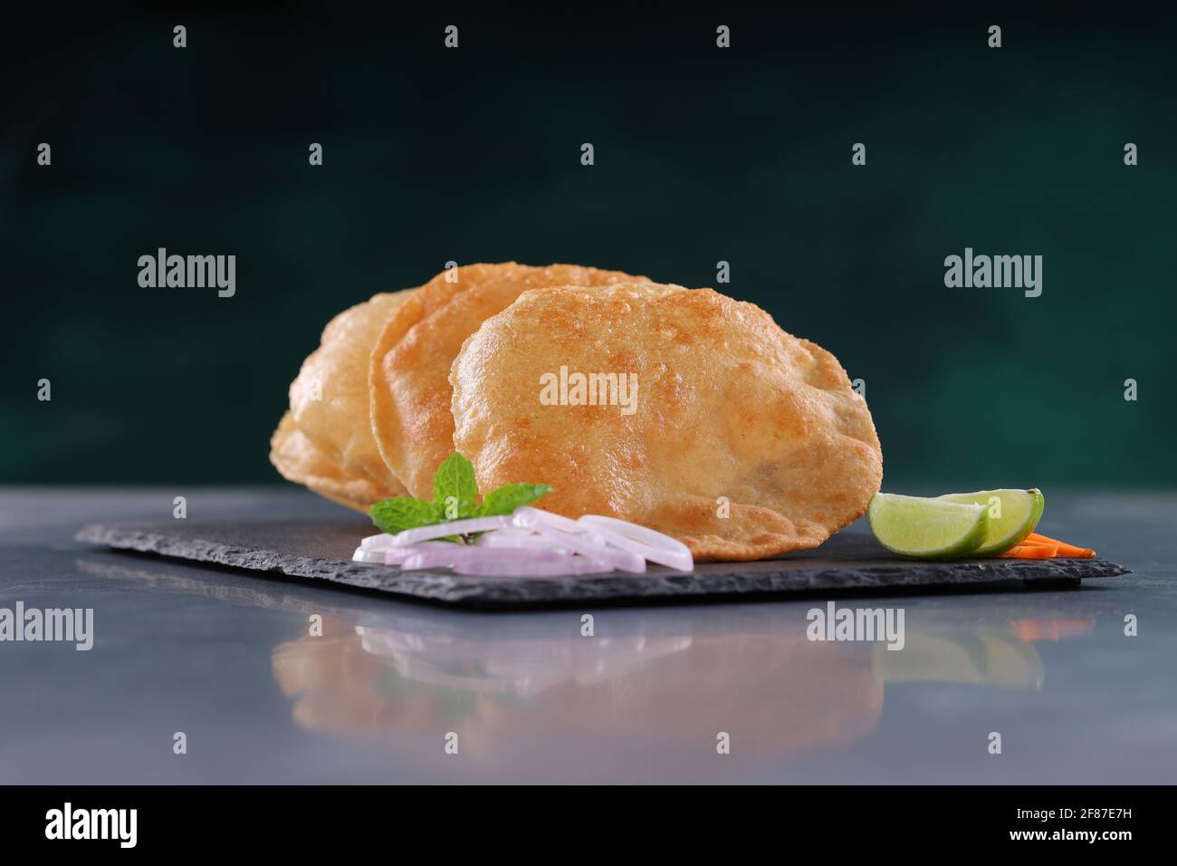 Indian breakfast  Poori or puri ,tasty indian dish made using all purpose wheat flour which is arranged in a slate with grey textured background. Stock Photo