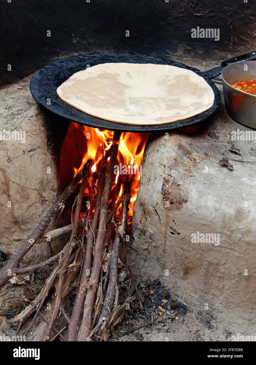 https://c8.alamy.com/comp/2F87EBB/wooden-fire-burning-in-hand-made-mud-stove-with-bread-roti-is-being-baked-on-desi-tawa-village-2F87EBB.jpg