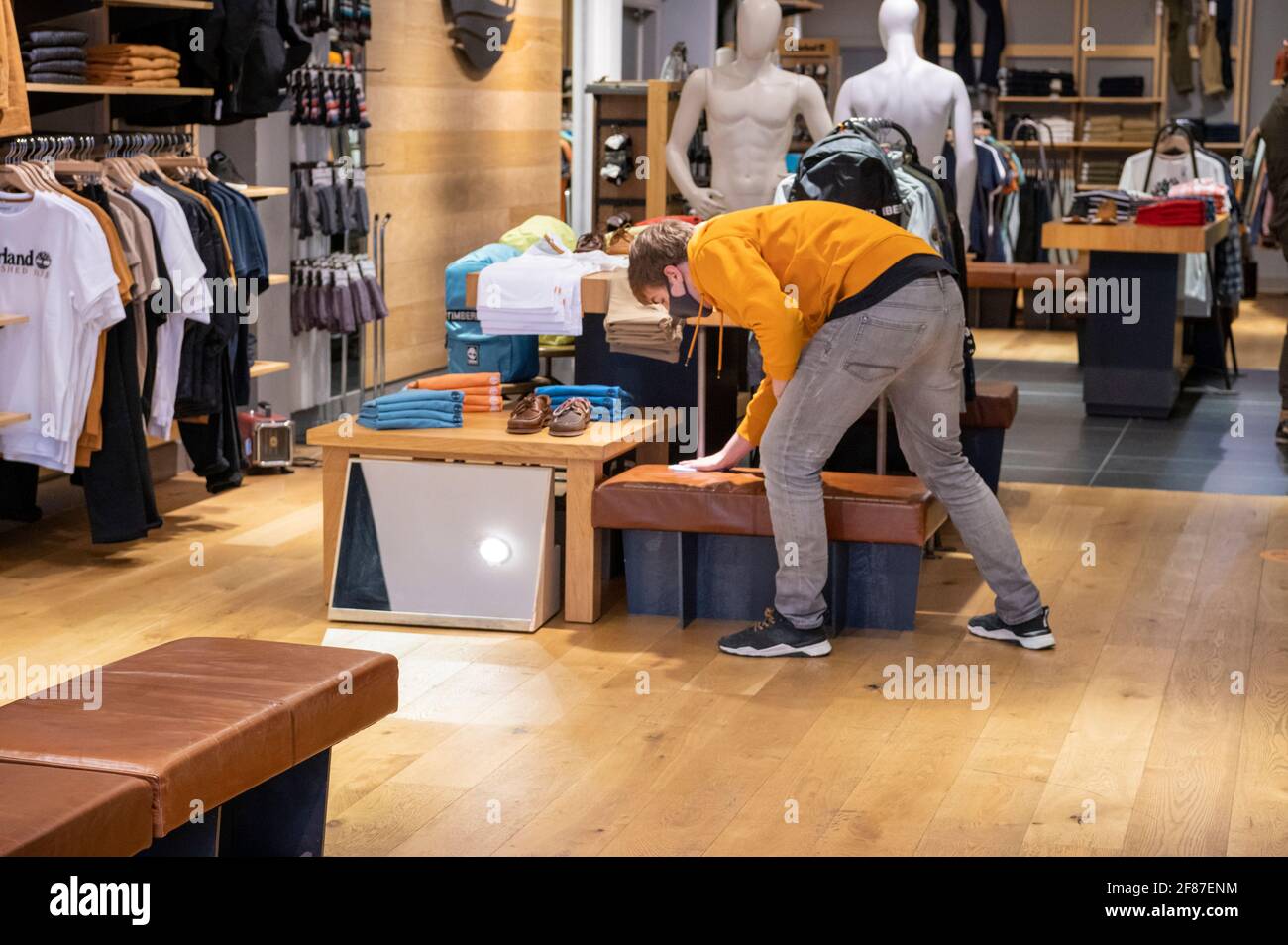 Cambridge, UK. 12th Apr, 2021. A member of staff cleans inside Timberland  clothes store as shops reopen in Cambridge as part of the UK easing of  Covid 19 lockdown restrictions. The roadmap