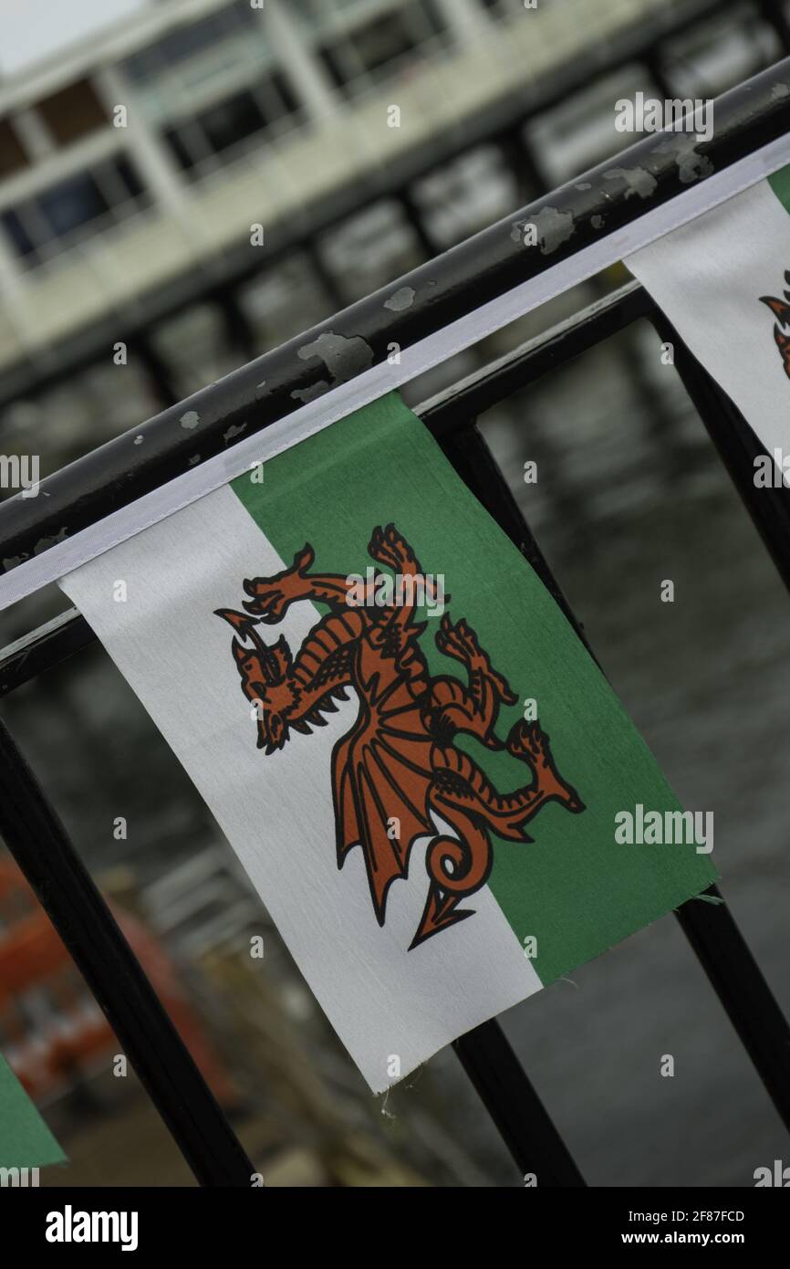 Vertical shot of the flag of Wales with a red dragon on a bridge railing Stock Photo