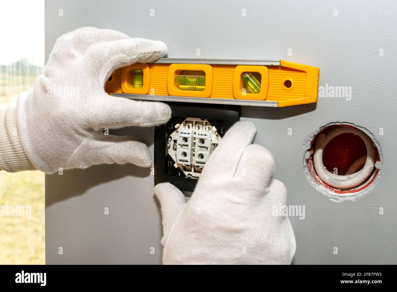 An electrician mounts the black frame of the roller shutter switch up ...