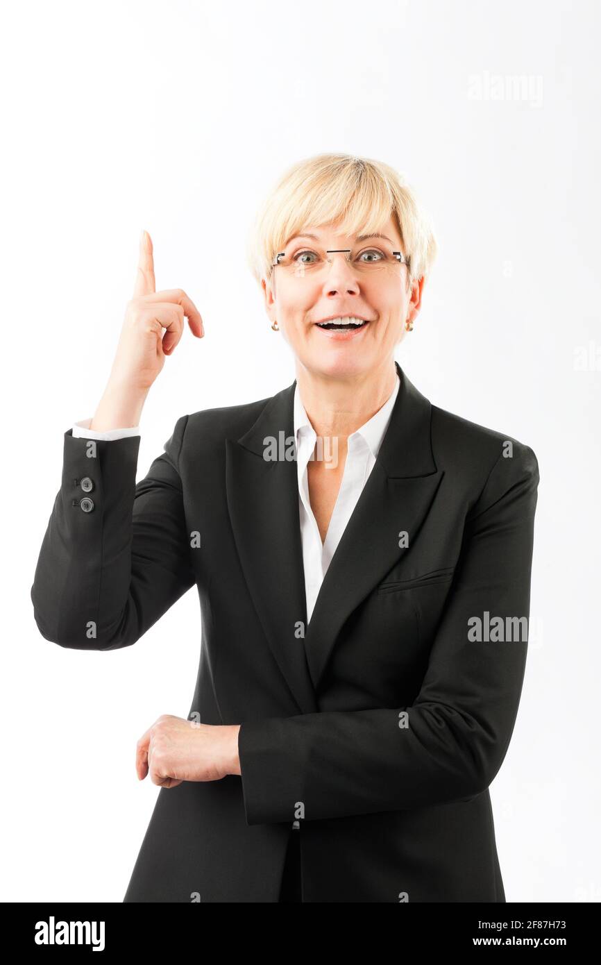 Portrait of happy mature businesswoman pointing finger upward against ...