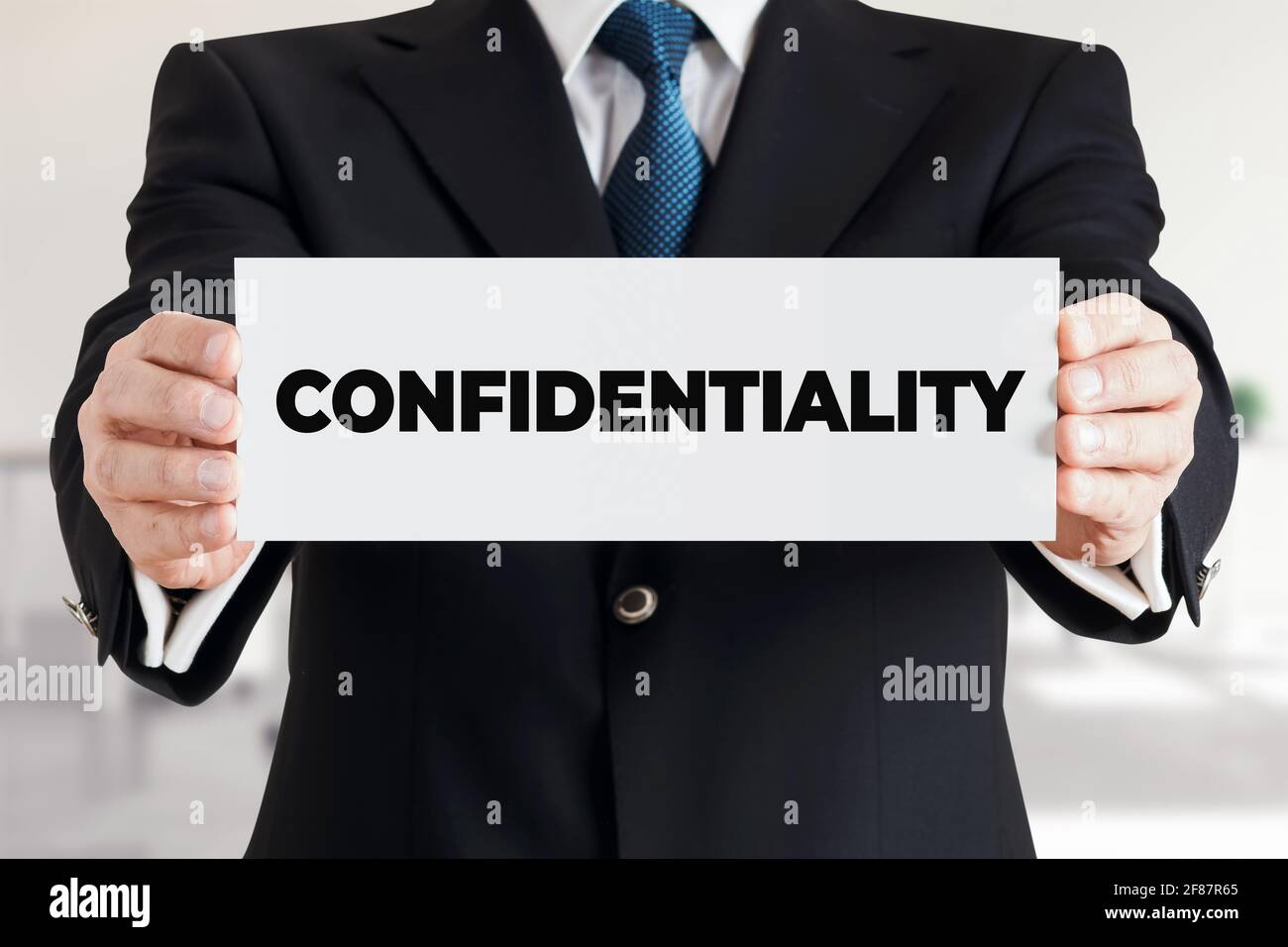 Businessman shows a banner with the word confidentiality. Business data or information secrecy protection concept. Stock Photo
