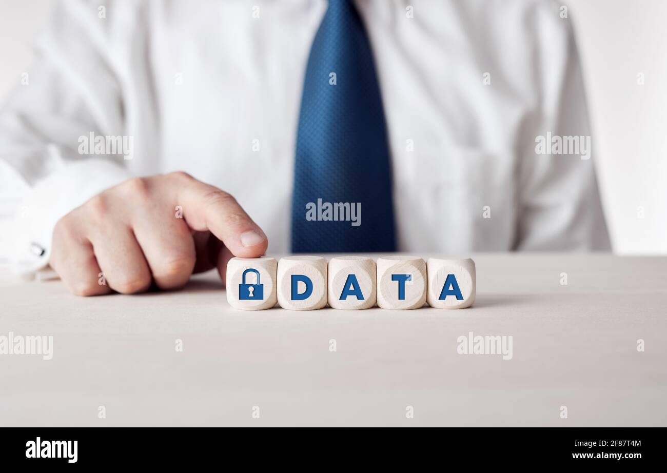 Data security concept. Businessman pressing his finger on the wooden cubes with the word data and a padlock icon. Stock Photo