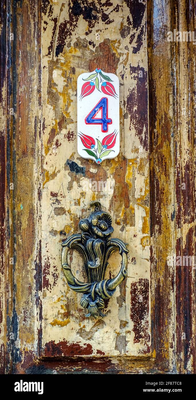 The doorknob and the number four inscription stand on the old wooden historical door, selective focus Stock Photo