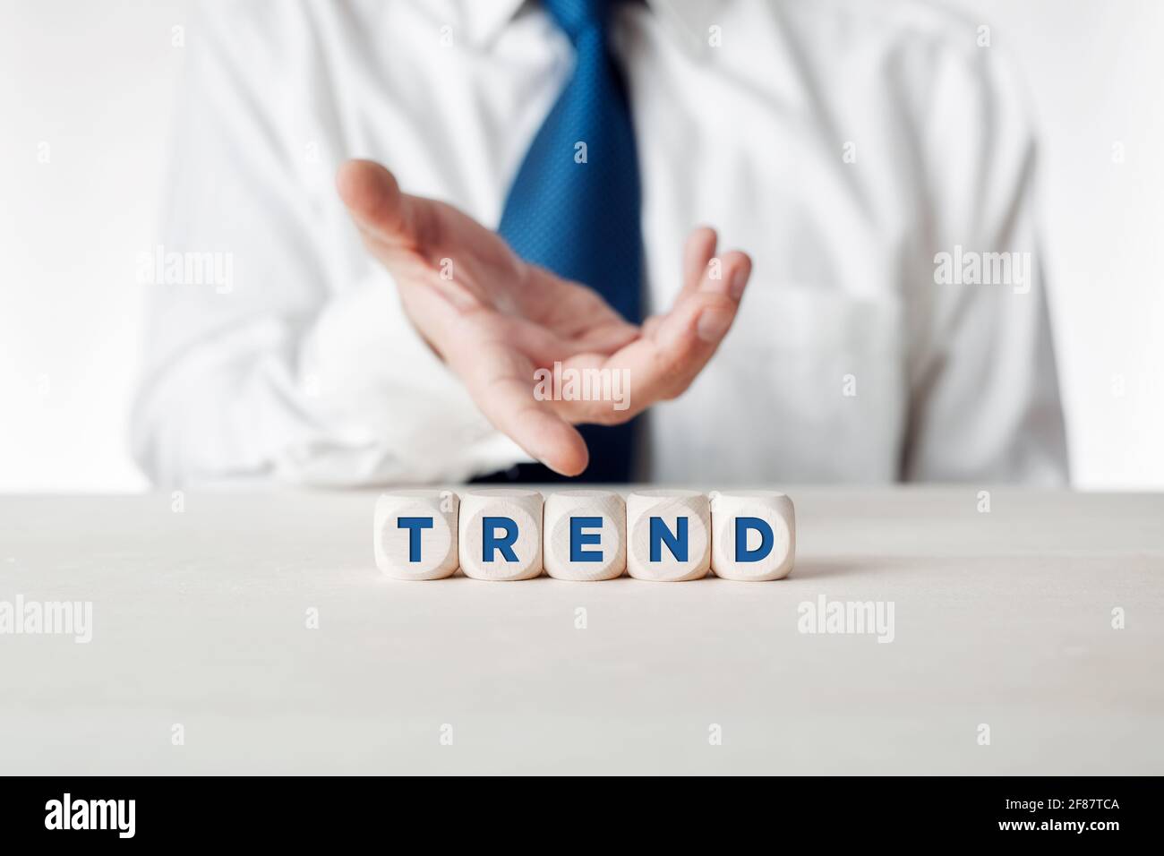 Hand of a businessman presenting the wooden cubes with the word trend. Popular new topics, trends, themes, styles and new technologies. Stock Photo