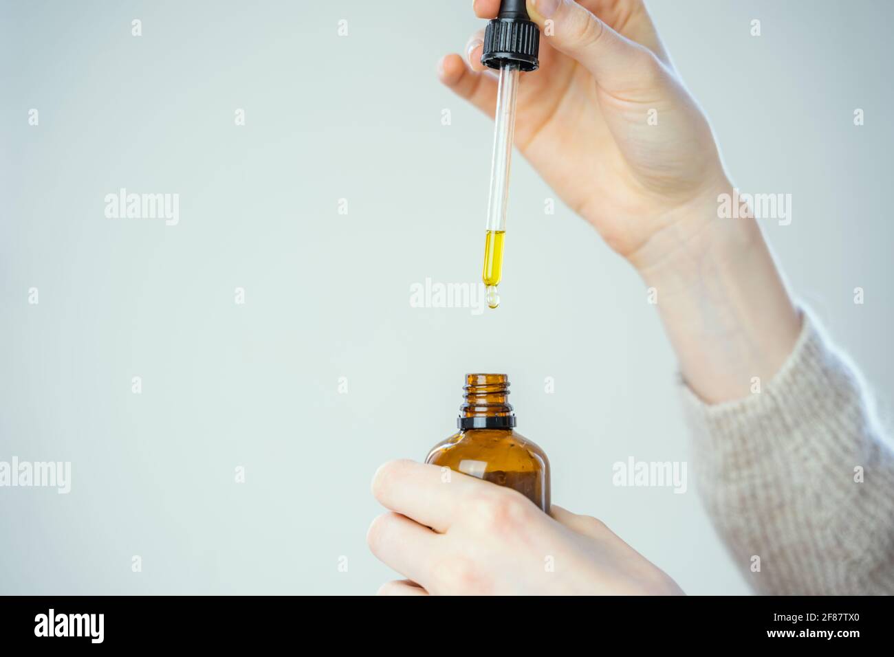 close up of droplet dosing a biological and ecological hemp plant herbal pharmaceutical cbd oil from a jar. Stock Photo