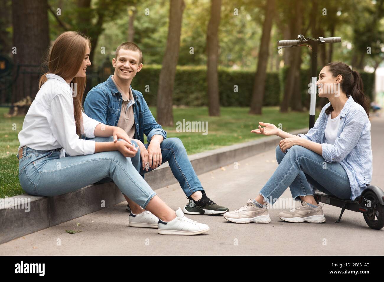 Three friends spending time in park and talking Stock Photo